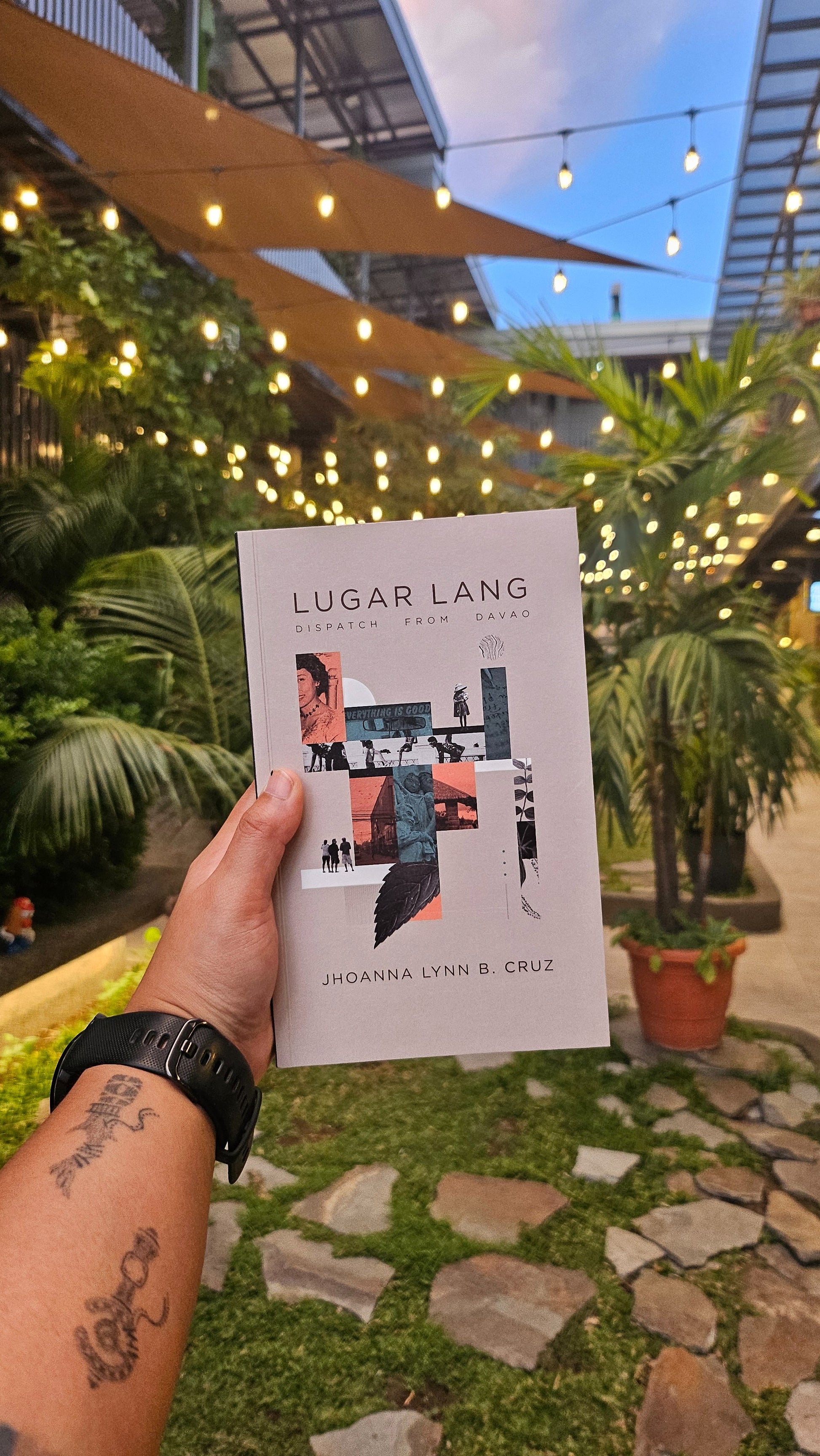 A person's hand holding a book titled 'Lugar Lang: Dispatch from Davao' by Jhoanna Lynn B. Cruz